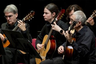 drei Personen in schwarzer Kleidung spielen Gitarre