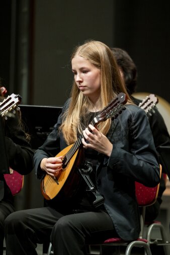 ein Mädchen in schwarzer Kleidung spielt Mandoline
