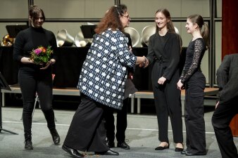 eine Frau reicht einem Mädchen die Hand zur Gratulation, weitere Personen stehen dabei