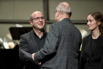 zwei Männer reichen sich die Hand zur Gratulation