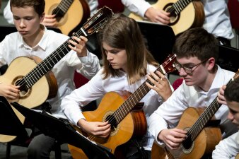 junge Mitglieder eines Gitarrenrorchesters mit weißen Hemden beim Vorspiel