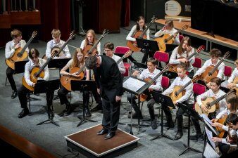 ein Gitarrenorchester auf der Bühne, der Digirent verneigt sich Richtung Publikum