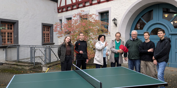 Vorstand des Fördervereins und Musikschüler stehen um Tischtennisplatte und nehmen Schläger und Bälle entgegen.
