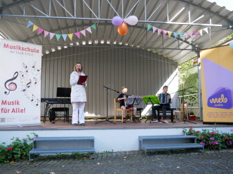 Ansagerin auf der bunt geschmückten Bühne