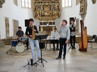 Ensemble aus Saxophon, Gesang, Schlagwerk und Klavier
