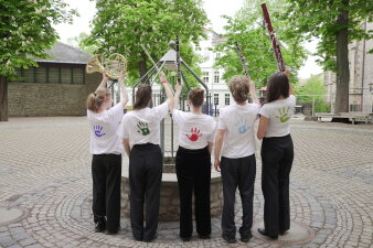 Schüler mit Blasinstrumenten von hinten - bunte Hände auf dem Rücken