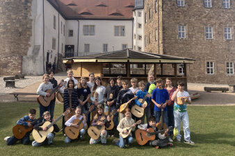 Kinder mit Mandolinen und Gitarren vor der Wasserburg