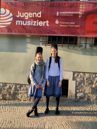 schülerinnen mit Gitarre vor einem Banner