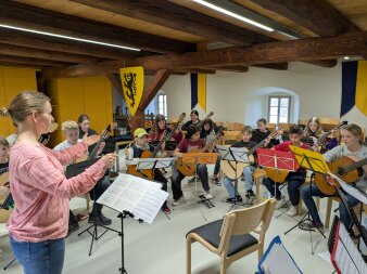 Kinder mit Mandolinen und Gitarren dirigiert von ihrer Lehrerin