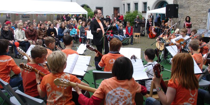 Das Kinderzupforchester spielt im Schulhof vor vielen Gästen