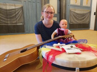 Lehrerin mit Babypuppe umgeben von Gitarre und elementaren Instrumenten