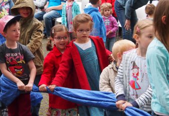 Kinder formen aus einem langen blauen Tuch einen Fluss.