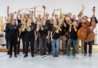 Musikerinnen der Big Band halten ihre Instrumente nach oben