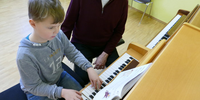 Kind mit Lehrer am Klavier