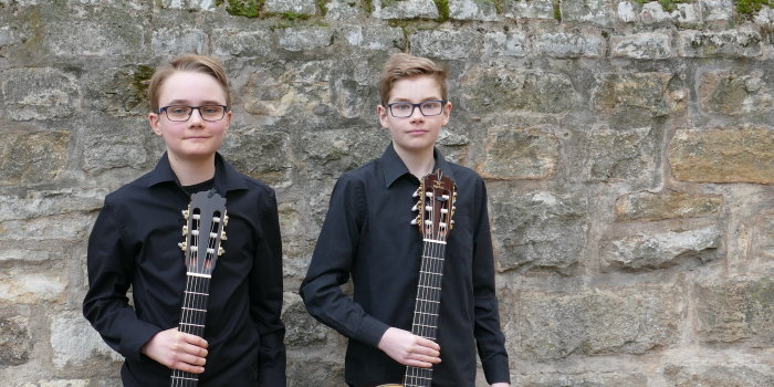 zwei Jungen mit Gitarren im Hof der Musikschule.