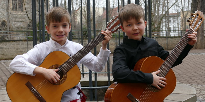 zwei Jungen spielen auf ihren Gitarren.