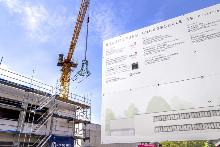 Das Foto zeigt das Bauschild und den Rohbau zum Richtfest.