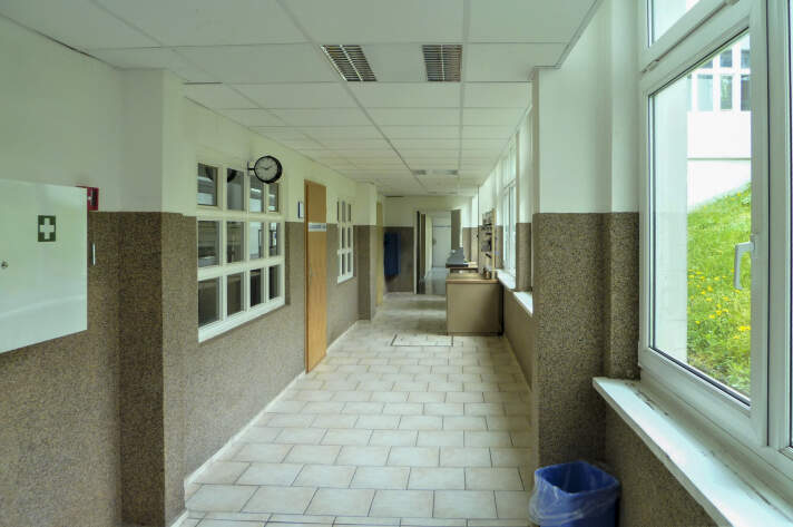 Das Foto zeigt den Schulflur mit braun-weißen Wänden und Fliesenboden.