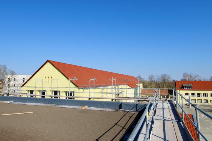 Das Foto zeigt das Gründach der Sporthalle mit Blick auf das Schulgebäude.
