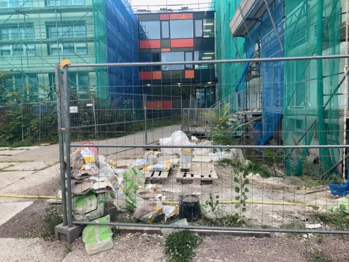 Das Foto zeigt das Schulgebäude, welches von einem Baugerüst eingeschlossen ist.