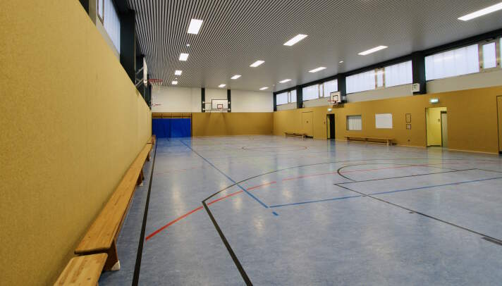 Das Foto zeigt die Sporthalle mit blauem Boden und gelben Wänden.