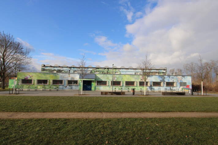 Das Foto zeigt die energetisch sanierte Sporthalle mit bemalter Außenfassade.