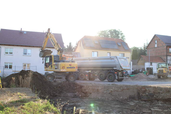 Das Foto zeigt einen Bagger, der Erde in einen Transporter lädt.
