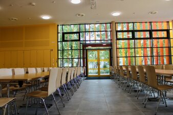 Das Foto zeigt die neue Mensa der Riethschule mit Tischen und Stühlen.