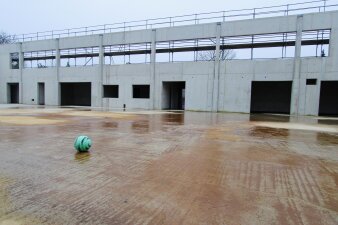Das Foto zeigt einen grünen Fußball in dem entstehenden Rohbau der Sporthalle.