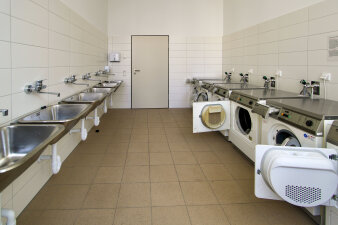 Das Foto zeigt den Hauswirtschaftsraum mit mehreren Waschmaschinen und Waschbecken.