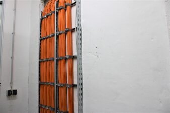 Das Foto zeigt viele Kabelstränge, welche an der Wand verlaufen.