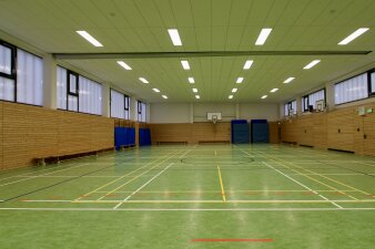 Das Foto zeigt die sanierte Sporthalle mit grünem Hallenboden.
