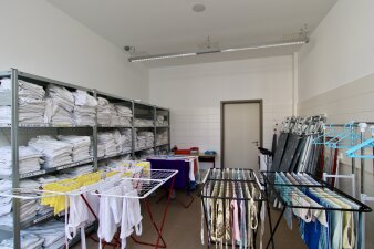 Das Foto zeigt den Hauswirtschaftsraum mit einem Regal mit gewaschener Wäsche und gefüllten Wäscheständern.