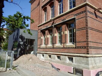 Das Foto zeigt das Schulgebäude in der Außenansicht während der Abdichtungsarbeiten.
