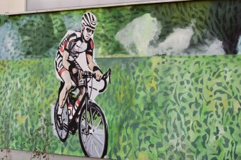 Das Foto zeigt einen Radfahrer, der auf die Außenseite der Sporthalle gemalt wurde.