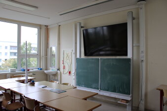 Das Foto zeigt einen Klassenraum mit Fernseher an der Wand.