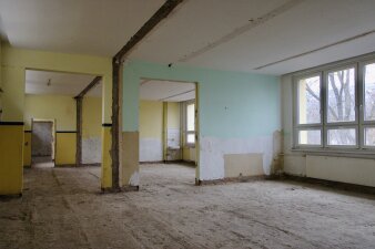 Das Foto zeigt zwei entkernte Unterrichtsräume mit gelben  und grünen Wänden.