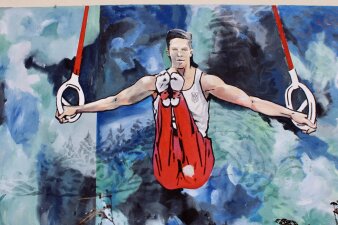 Das Foto zeigt einen Turner, der auf die Außenseite der Sporthalle gemalt wurde.