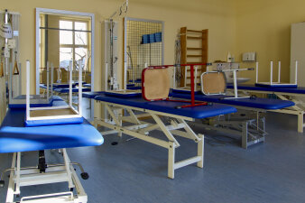 Das Foto zeigt verschiedene Spiegel, eine Sprossenwand und Therapieliegen zu Physiotherapie-Zwecken.
