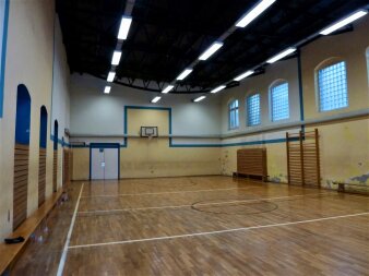 Das Foto zeigt die Sporthalle mit Holzboden vor der Sanierung.