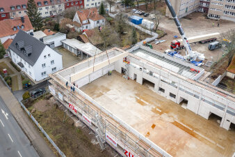 Das Foto zeigt eine Luftbildaufnahme der Sporthalle, während ein Dachbinder montiert wird.