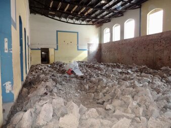 Das Foto zeigt die Sporthalle während der Abbrucharbeiten mit großen Steinen in der gesamten Halle.