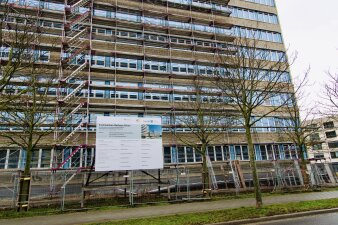 Das Foto zeigt die Warsbergstraße 1 während der Sanierung mit Baugerüst und Baustellenschild.