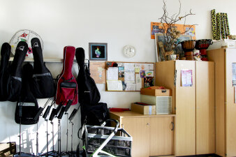Das Foto zeigt den Musikraum mit Notenständern, Gitarren und Trommeln.