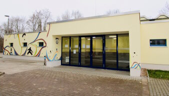 Das Foto zeigt den Eingangsbereich der Sporthalle von außen mit bund bemalter Fassade.