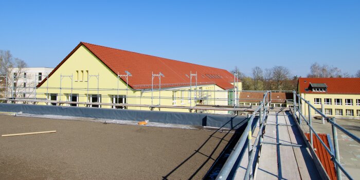 Das Foto zeigt das Gründach der Sporthalle mit Blick auf das Schulgebäude.