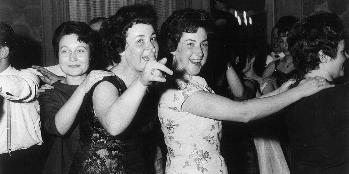 Foto: Fröhliche Betriebsfeier des Bezirksbauamtes im Jahre 1963 © Stadtverwaltung Erfurt/Stadtarchiv Drei Frauen tanzen in einer Polonaise