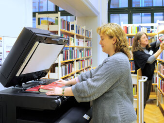 Eine Frau scannt ein Buch mit dem Kopierer.
