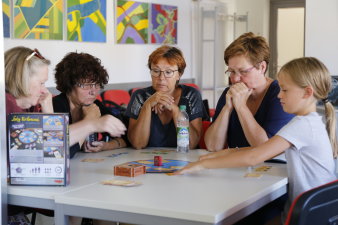 vier Frauen und ein Mädchen an einem Tisch beim Spielen