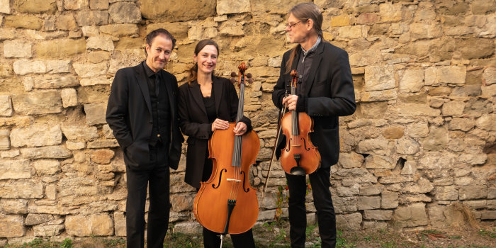 Foto: Susanne V. Thiele (Violoncello), Klaus Heydenbluth (Rezitation) und Axel D. Wolf(Viola) laden herzlich ein © Sven Wachsmuth Drei schwarz gekleidete Künstler stehen mit ihren Streichinstrumenten vor einer Steinmauer